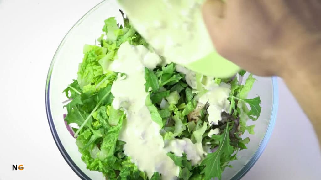 adding gluten free Caesar Dressing in salad